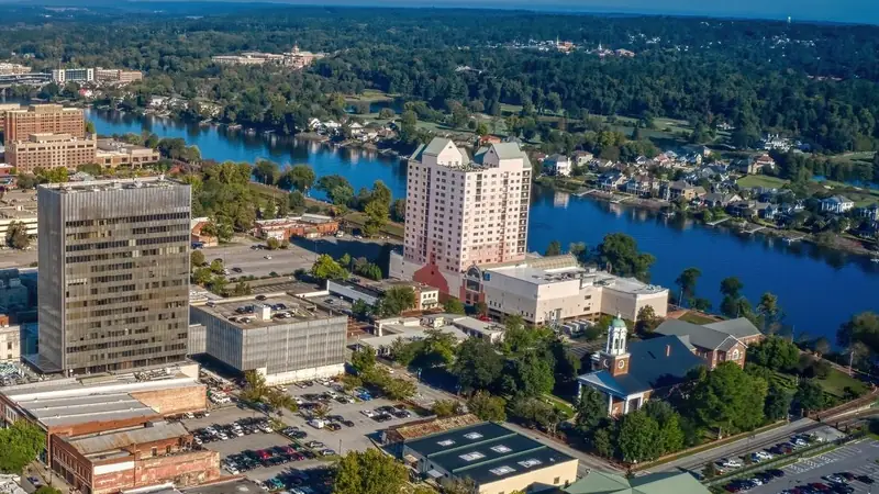 Downtown Augusta, Georgia seen from the air, with office towers and a domed church beside the Savannah River and tree-covered banks beyond
